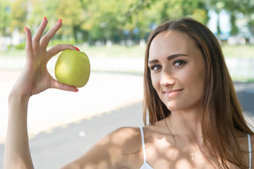 Secret of her beauty is healthy nutrition. Girl dieting or support vegetarian lifestyle. Fruits contain important for human body vitamins and acids. Woman adorable and healthy holds green apple