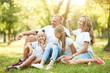 © Anton - Cheerful family sitting on the grass during a picnic in the park