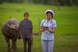 © somchai20162516 - Beautiful nurse smiling and holding a tablet with headphones standing behind the Asian peasant.