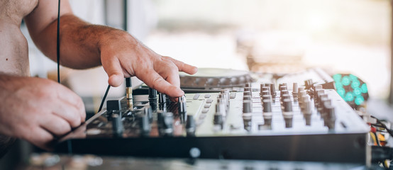 Closeup of DJ hands plays music on player and mixer