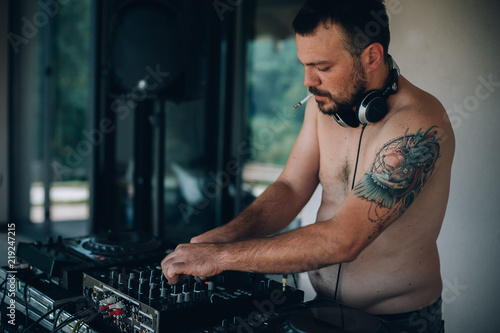 DJ smoke cigarette and plays music on player and mixer Wallpaper Mural