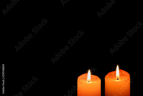Fotografiet A pair of vivid orange color candles burning in the dark, with free space for te