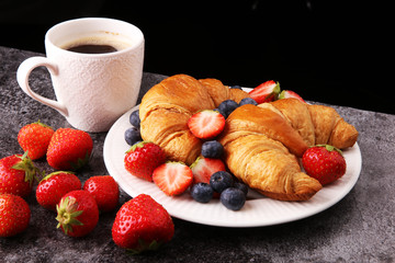 Delicious breakfast with fresh croissants and ripe berries on old marble background