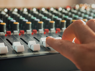 Man adjusting fade sliders on audio mixer