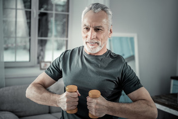 Wall Mural - Morning exercise. Cheerful senior male expressing positivity while working in gym