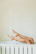 © LIGHTFIELD STUDIOS - low section of young woman relaxing in bathtub with foam