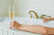 © LIGHTFIELD STUDIOS - cropped shot of young woman holding glass of champagne in bathtub