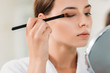 © LIGHTFIELD STUDIOS - close-up view of beautiful young woman applying eyeshadow with brush