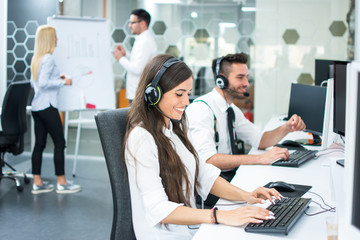 Smiling customer support operators working on computers at office.