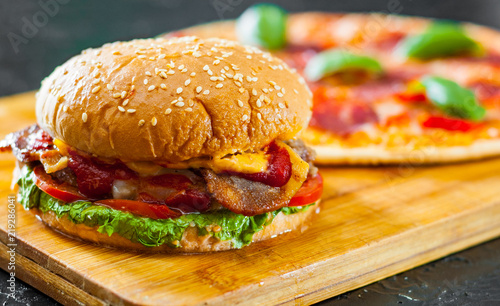 bacon cheese burger with beef patty tomato onion and Pizza with Mozzarella cheese, Ham, Tomatoes, salami, pepper, pepperoni Spices and Fresh Basil © pavel siamionov