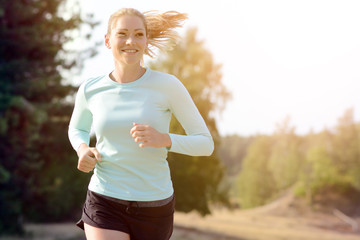 Sporty girl in sportswear jogging, running and training outdoors on a sunny day in summer