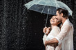 © LIGHTFIELD STUDIOS - side view of romantic couple in white shirts standing under umbrella under raindrops isolated on black