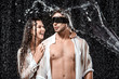 © LIGHTFIELD STUDIOS - portrait of man with black ribbon on eyes and smiling girlfriend while swilled with water isolated on black