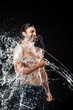 © LIGHTFIELD STUDIOS - smiling young man showing thumb up while swilled with water splash isolated on black