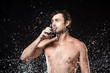 © LIGHTFIELD STUDIOS - portrait of shirtless man drinking water from glass while swilled with water isolated on black