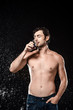 © LIGHTFIELD STUDIOS - portrait of shirtless man drinking water from glass while swilled with water isolated on black