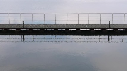 Poster - A wooden bridge over the lake. Grass and reeds in the background. Gentle waves.  Panning,Closeup, 