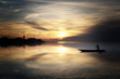 Laguna di Venezia al tramonto. Nelle placide acque un pescatore passa vogando nella sua gondola.