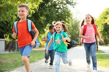 Poster - Cute little children with backpacks running outdoors. Elementary school