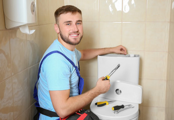 Poster - Professional plumber in uniform repairing toilet tank indoors