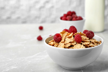 Bowl with cornflakes and raspberries on gray table. Whole grain cereal for breakfast