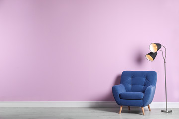 Poster - Comfortable armchair and lamp near color wall with space for text. Interior element