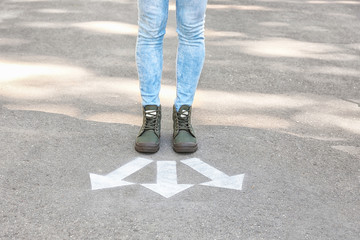 Wall Mural - Woman standing near arrows on asphalt. Choice concept