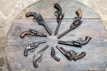 A group of ancient pistols on vintage wooden table..