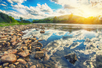 Wall Mural - Mountain river stream of water in the rocks with blue sky.