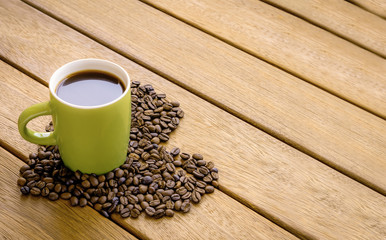 a cup of coffee over the wooden ground and coffee beans