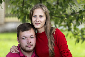 Close-up portrait of young attractive happy romantic smiling couple in love, pretty blond long-haired girl and handsome unshaven man hugging together outdoors on bright blurred sunny background.