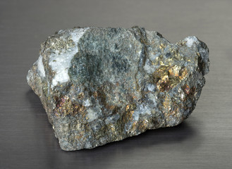 Wall Mural - Specimen of mineral chalcopyrite (copper pyrite) on gray background. Copper pyrite consisting of iron, copper, and sulfur. 