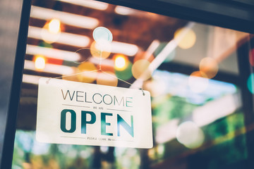 A business sign that says ‘Open’ on cafe or restaurant hang on door at entrance. Vintage color tone style.