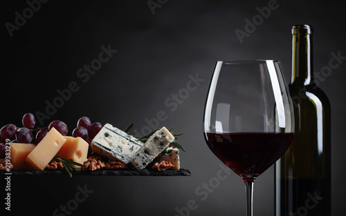 Plakat Kieliszek czerwonego wina z różnych serów, winogron i orzechów włoskich.