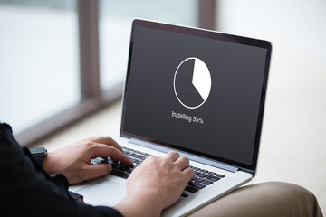 Man Installing update with circle load percentage waiting indicator concept on the laptop / computer screen at office