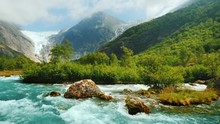 Briksdal Glacier With A Mountain River In The Foreground. The Amazing Nature Of Norway