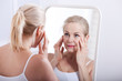 © missty - Middle aged woman looking at wrinkles in mirror. Plastic surgery and collagen injections. Makeup. Macro face. Selective focus