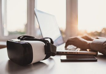Business man using laptop computer with VR headset. Focus on virtual reality glasses
