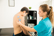 © AntonioDiaz - Therapist Placing Electrodes On Man's Shoulder In Clinic