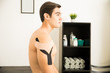 © AntonioDiaz - Shirtless Athlete With Kinesiology Tape On Shoulder In Clinic