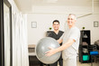 © AntonioDiaz - Patient Holding Exercise Ball By Physiotherapist In Hospital