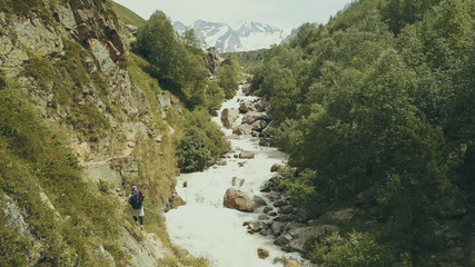 Wall Mural - mountain tourist walking along rapid river back view. hiking mountain