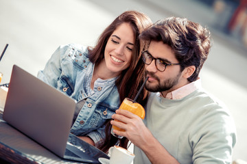 Wall Mural - Happy couple using laptop in cafe