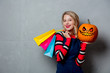 © Masson - Young style girl in jeans clothes with shopping bags and halloween pumpkin on grey background.