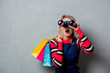 © Masson - Portrait of a young style blonde girl in red striped sweater with shopping bags and binoculars on grey background.
