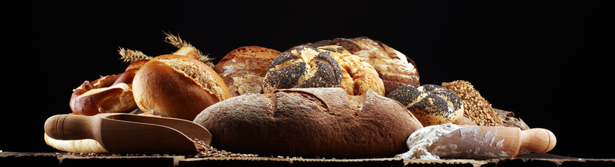 Different kinds of bread and bread rolls on board from above. Kitchen or bakery