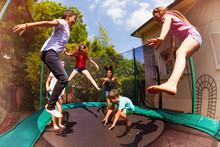 Happy Friends Jumping On The Trampoline In Summer
