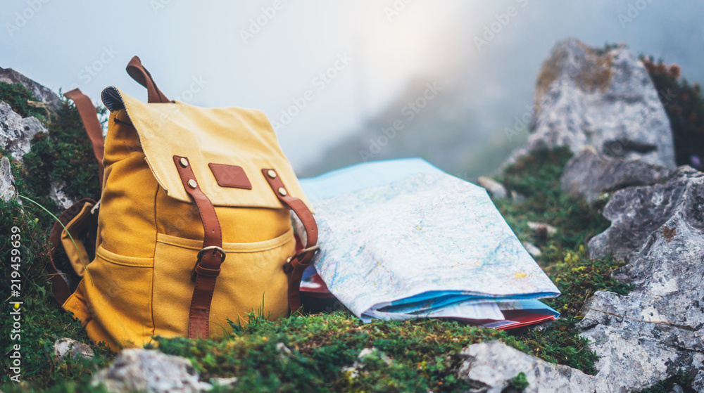 Hipster hiker tourist yellow backpack and map europe on background green grass nature in mountain, blurred panoramic landscape, traveler relax holiday concept, view planning wayroad in trip vacation - obrazy, fototapety, plakaty 