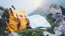 Hipster Hiker Tourist Yellow Backpack And Map Europe On Background Green Grass Nature In Mountain, Blurred Panoramic Landscape, Traveler Relax Holiday Concept, View Planning Wayroad In Trip Vacation
