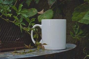 Wall Mural - A blank empty coffee mug on the overgrown backyard garden table in the evening.